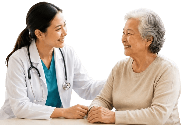 A clinician sitting with an older patient, holding her hand and smiling